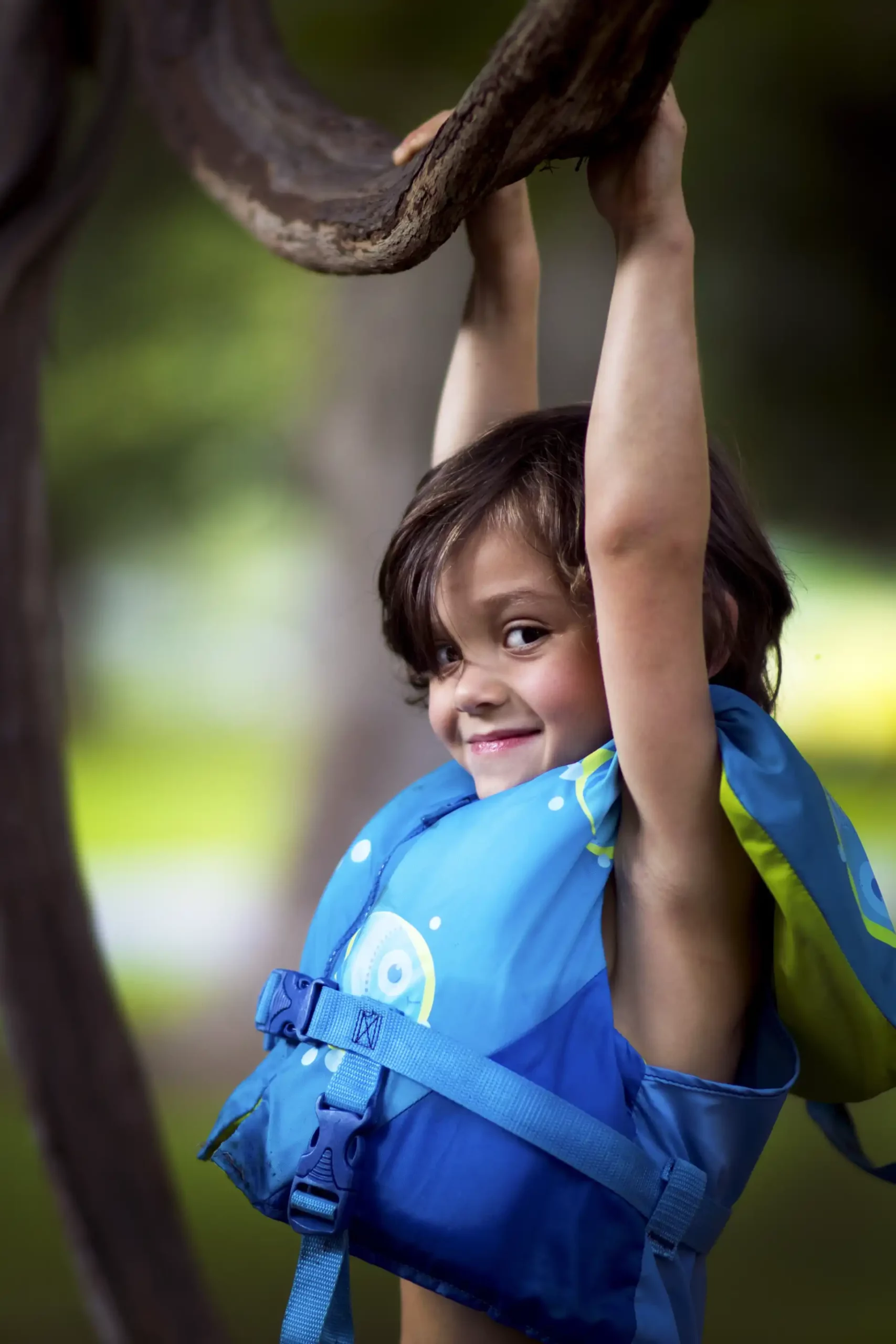 Free Happy Boy In Float Vest Hanging On Tree Branch Stock Photo